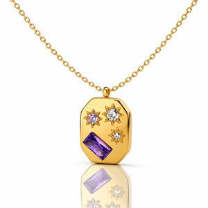 Gold necklace with a pendant featuring purple and clear gemstones on a white background