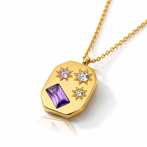 Gold necklace with a hexagonal pendant featuring purple and clear gemstones on a white background