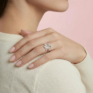 Close-up of a hand wearing a silver ring with a pink background