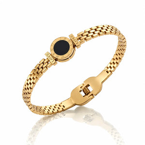 Gold bracelet with a black center on a white background