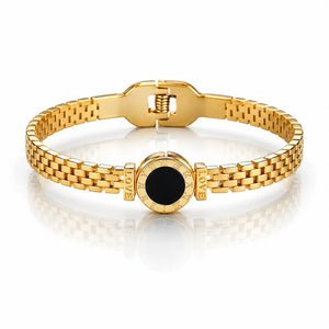 Gold bracelet with a black center on a white background