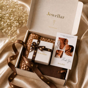Jewellery box with a bow and card on a satin surface, featuring the brand 'Jewellar'.