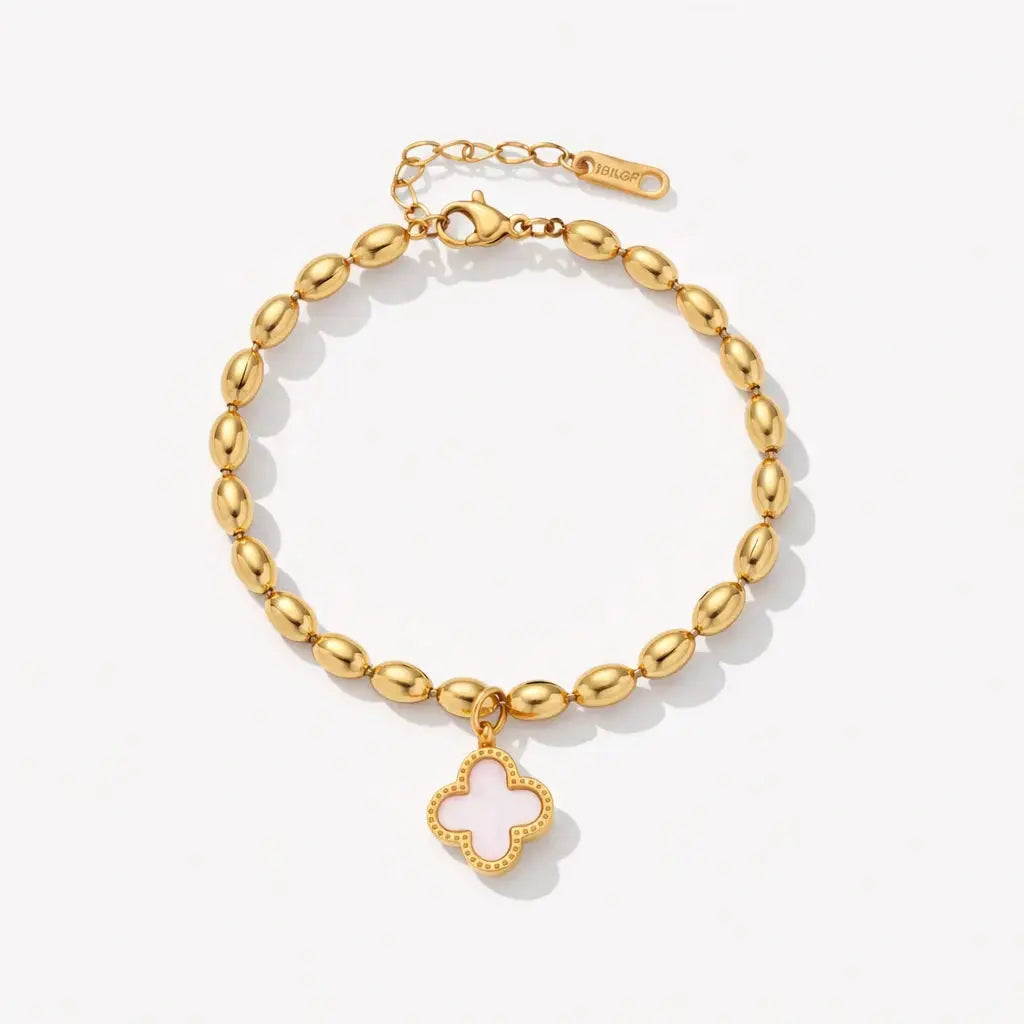Gold bracelet with a clover charm on a light gray background