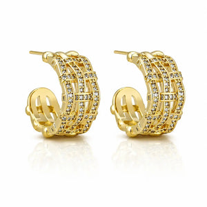 A pair of gold huggie hoop earrings adorned with multiple rows of clear pavé-set cubic zirconia stones, displayed on a clean white background with a soft reflection.