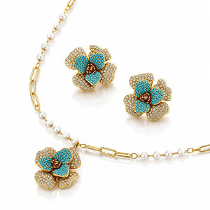 Gold-plated floral jewelry set featuring a necklace and matching earrings, decorated with turquoise blue stones, white pearls, and pavé-set clear crystals on a white background.
