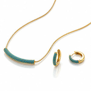 Gold jewelry set featuring a curved bar necklace and matching huggie hoop earrings, both adorned with a row of small turquoise-blue stones on a white background.