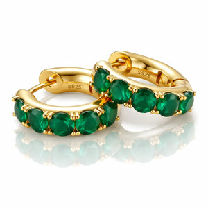 Gold hoop earrings with green gemstones on a white background