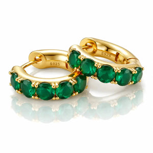 Gold hoop earrings with green gemstones on a white background