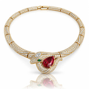 A luxury gold-plated snake-head pendant necklace paved with diamonds, featuring a large pear-cut red ruby center stone and a small green emerald accent, displayed on a clean white background with a soft reflection.