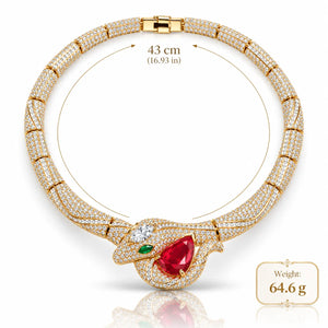 Gold-plated snake pendant necklace paved with small clear stones, featuring a large red pear-cut gemstone, a small green oval gemstone, and a clasp closure. The image includes a size measurement of 43 cm and a weight label of 64.