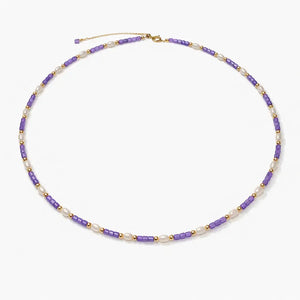 Violet beaded necklace with pearl accents and gold details on a white background