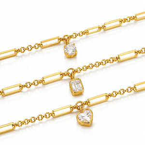 Three gold chain bracelets with rectangular bar links, each featuring a clear gemstone charm in a different shape: oval, emerald, and heart, displayed on a white background.