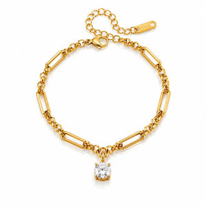 A gold chain bracelet with alternating paperclip and oval links, featuring a single square-cut clear gemstone pendant, displayed on a clean white background.