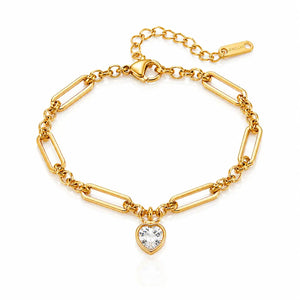 A gold paperclip chain bracelet with a heart-shaped clear crystal pendant, displayed on a clean white background.