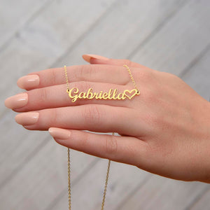 Close-up of custom name necklace with heart detail held in hand