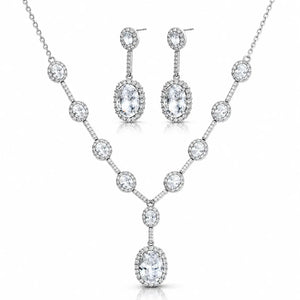 A silver-tone jewelry set featuring a V-shaped necklace and matching drop earrings, both adorned with clear round and oval gemstones, shown on a plain white background.