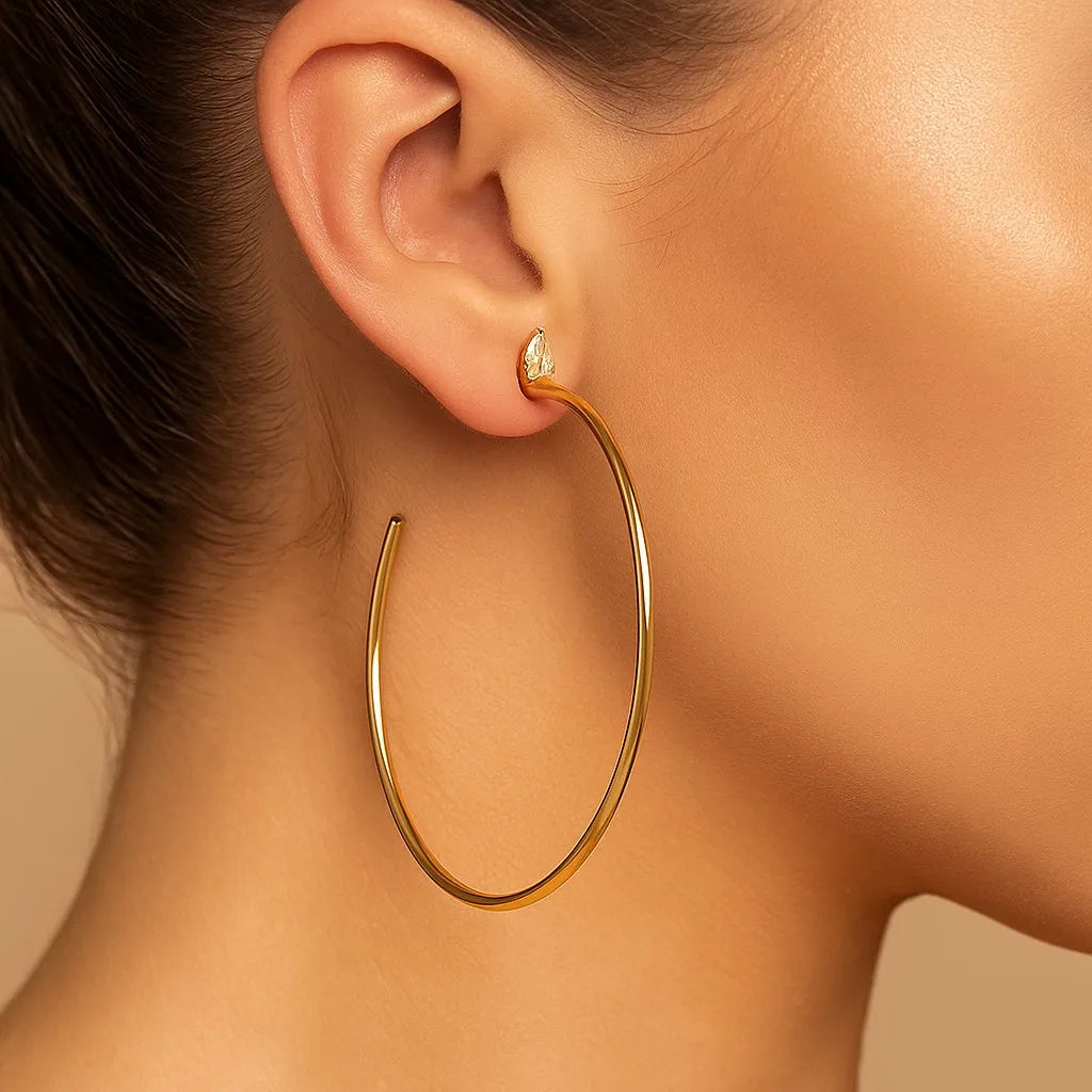Large gold hoop earring worn on ear, minimalist jewelry style, close-up on model