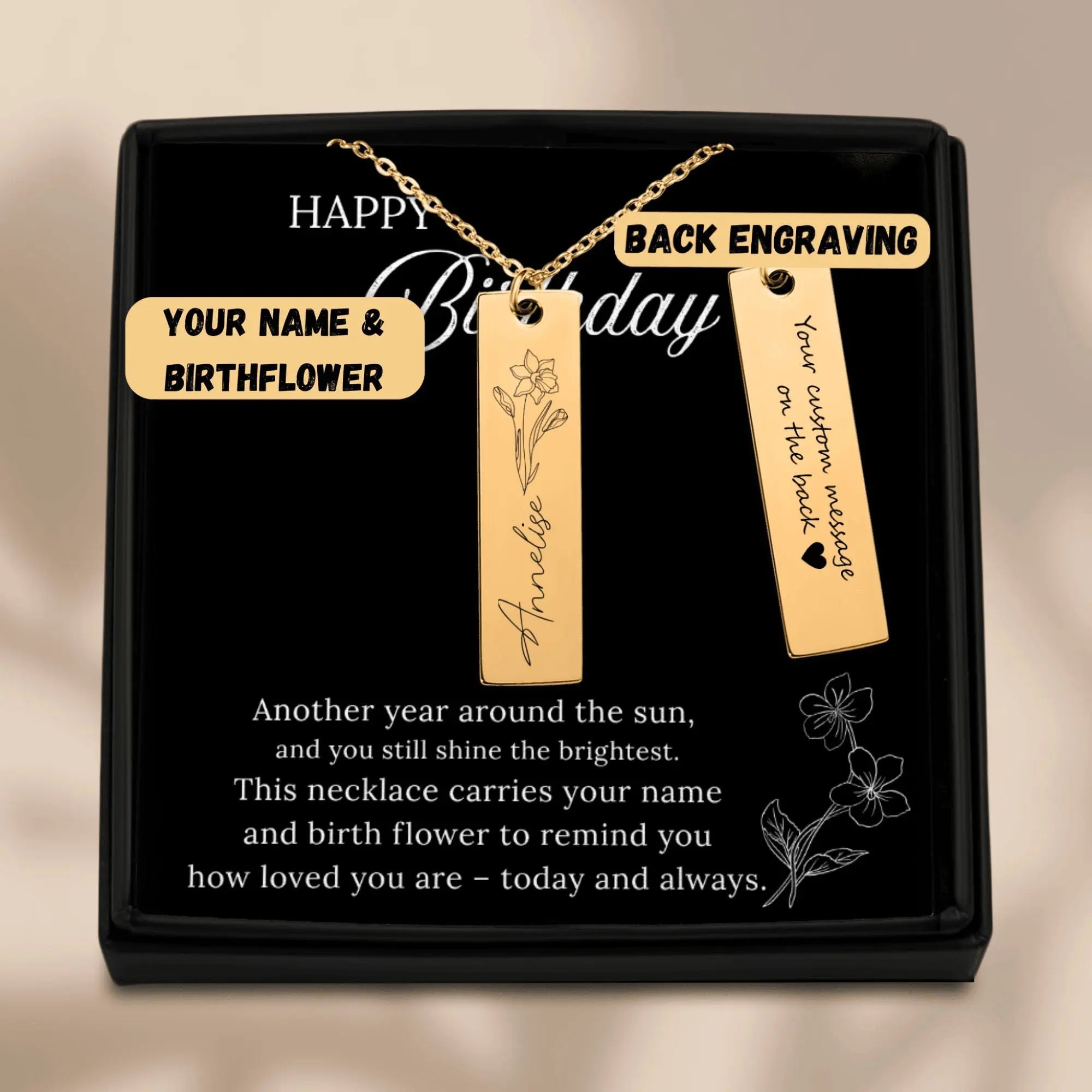 Gold necklace with engraved name and birthflower in a black gift box.