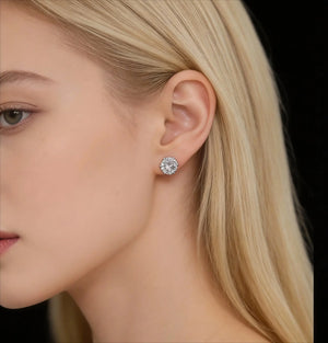 Close-up of a blonde woman wearing a sparkling silver stud earring against black background