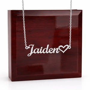 Silver necklace with 'Jaiden' and a heart pendant on a wooden box
