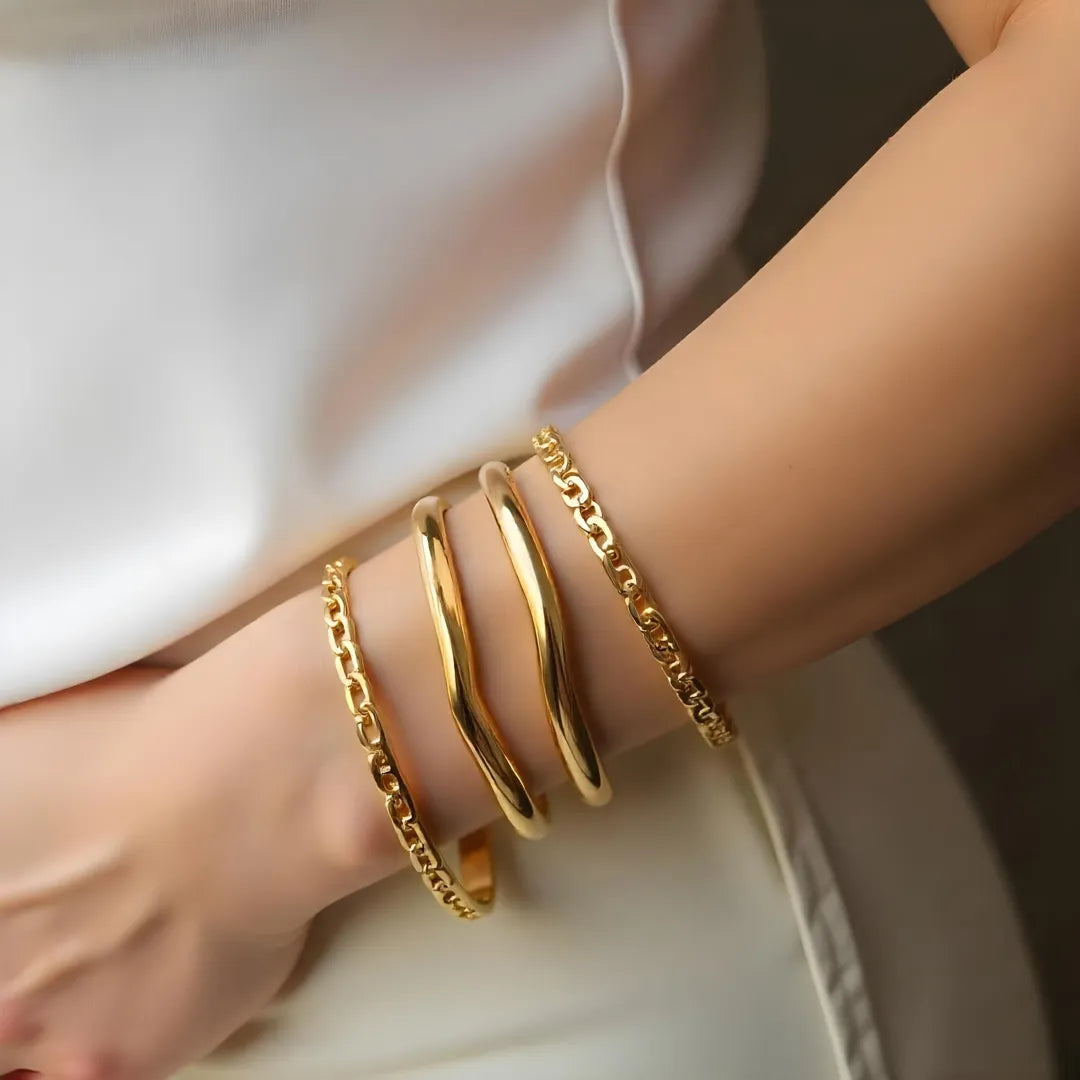 Woman wearing elegant gold bangles and chain bracelets on her wrist