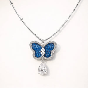 Butterfly pendant necklace with blue gem and teardrop crystal on a white background