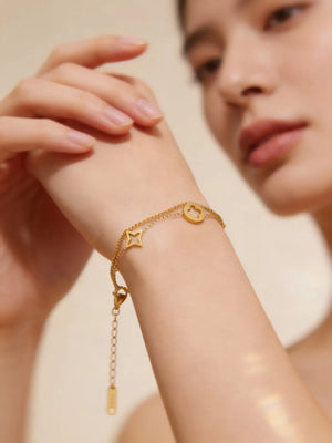 Woman wearing a delicate gold chain bracelet with star and clover charms