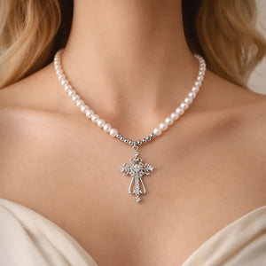 Pearl necklace with ornate silver cross pendant on woman's neck, elegant jewelry accessory