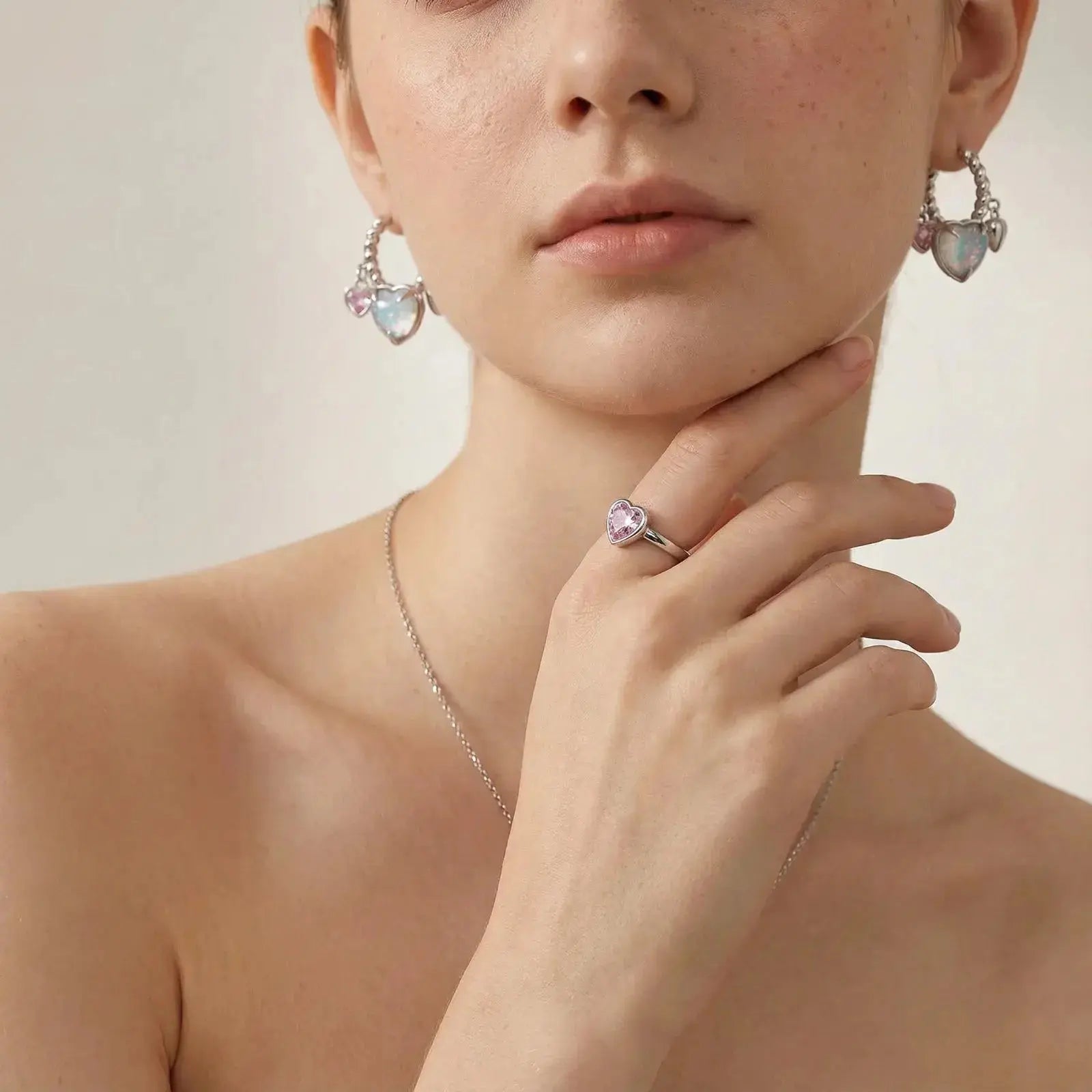 Woman wearing white gold heart-shaped opal hoop earrings and a matching heart ring