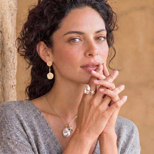 Woman with jewelry including earrings and a necklace, with a neutral background