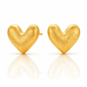 A pair of textured gold heart stud earrings on a clean white background with soft reflections below.