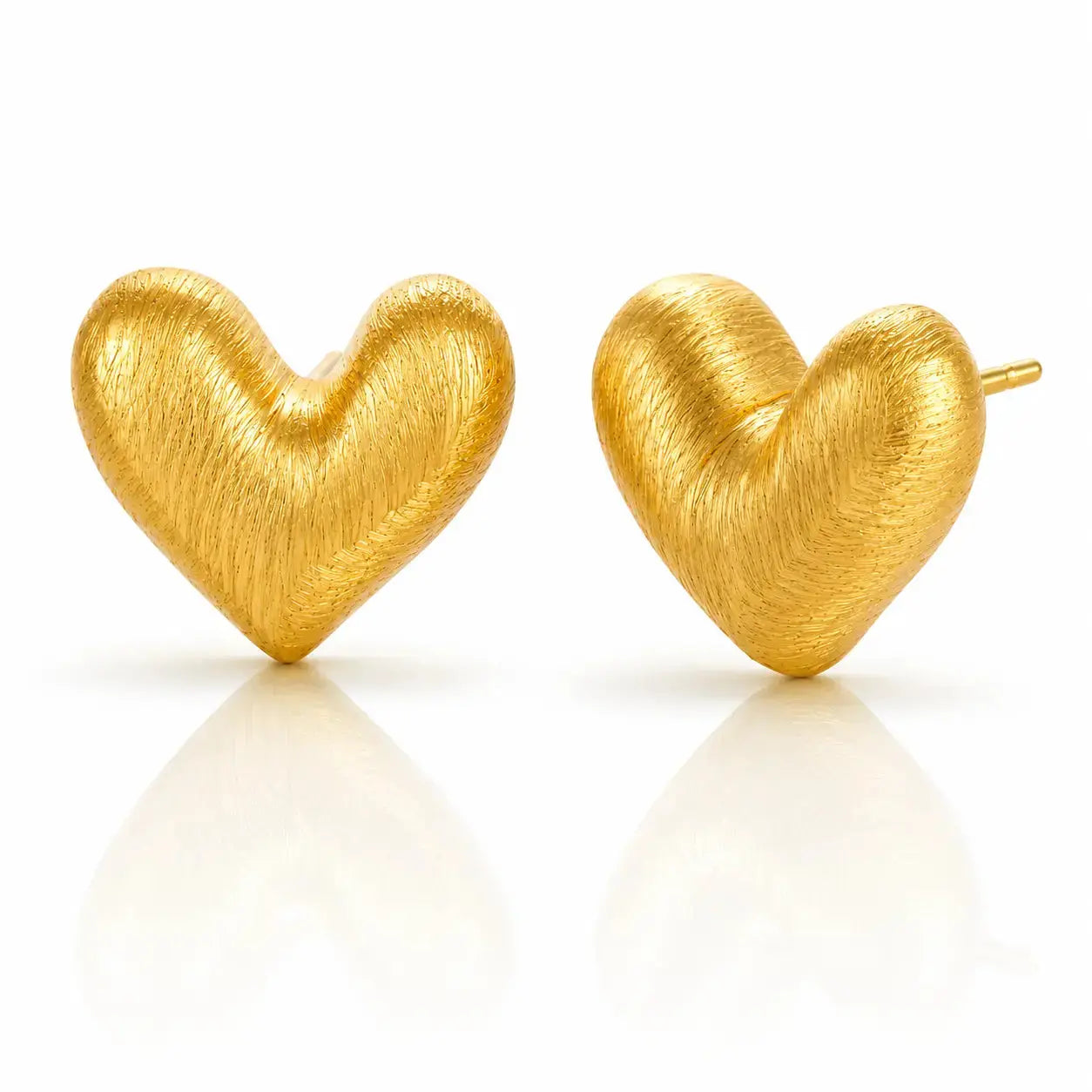 A pair of textured gold heart stud earrings on a clean white background with soft reflections below.