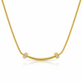 A gold necklace featuring a curved bar pendant flanked by two square bezel-set crystal clusters, suspended on a gold snake chain against a white background with a soft reflection.