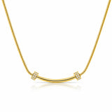 A gold necklace featuring a curved bar pendant flanked by two square bezel-set crystal clusters, suspended on a gold snake chain against a white background with a soft reflection.