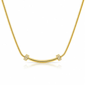 A gold necklace featuring a curved bar pendant flanked by two square bezel-set crystal clusters, suspended on a gold snake chain against a white background with a soft reflection.