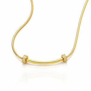 A gold snake chain necklace with a curved bar centerpiece, accented by two small square bezel-set crystal clusters on either end, shown on a white background with a soft reflection.