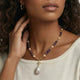 Woman wearing a gold amethyst and pearl necklace with large baroque pearl pendant