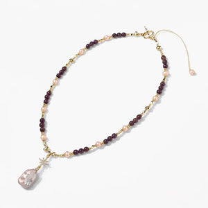 Gold amethyst and pearl necklace with a large baroque pearl pendant on white background