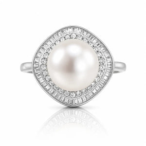 A silver ring featuring a large round white pearl surrounded by two halo rows of baguette-cut and round clear stones, shown on a white background with a soft reflection below.