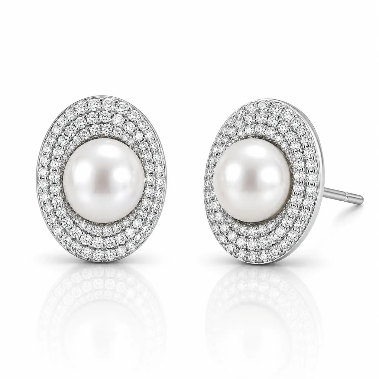A pair of oval stud earrings featuring a central white pearl surrounded by double rows of small clear pavé stones in a silver-toned setting, shown on a white reflective background.