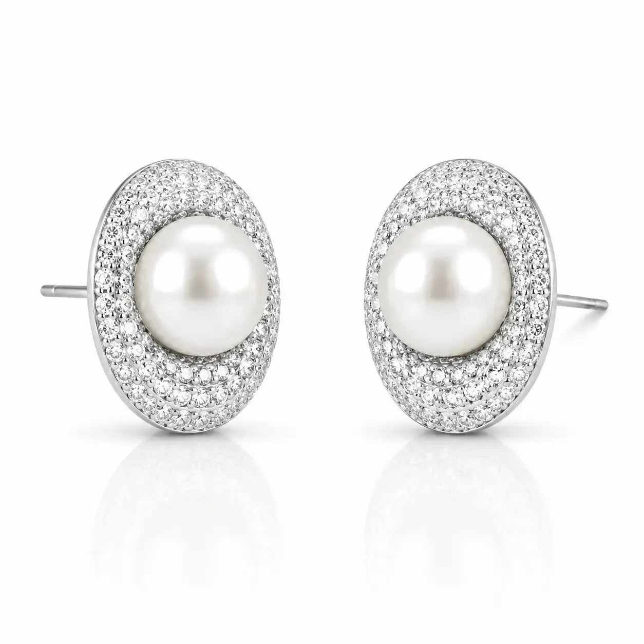 A pair of oval stud earrings featuring a central white pearl surrounded by a halo of small clear pavé stones in a silver-toned setting, shown on a clean white background with a soft reflection below.