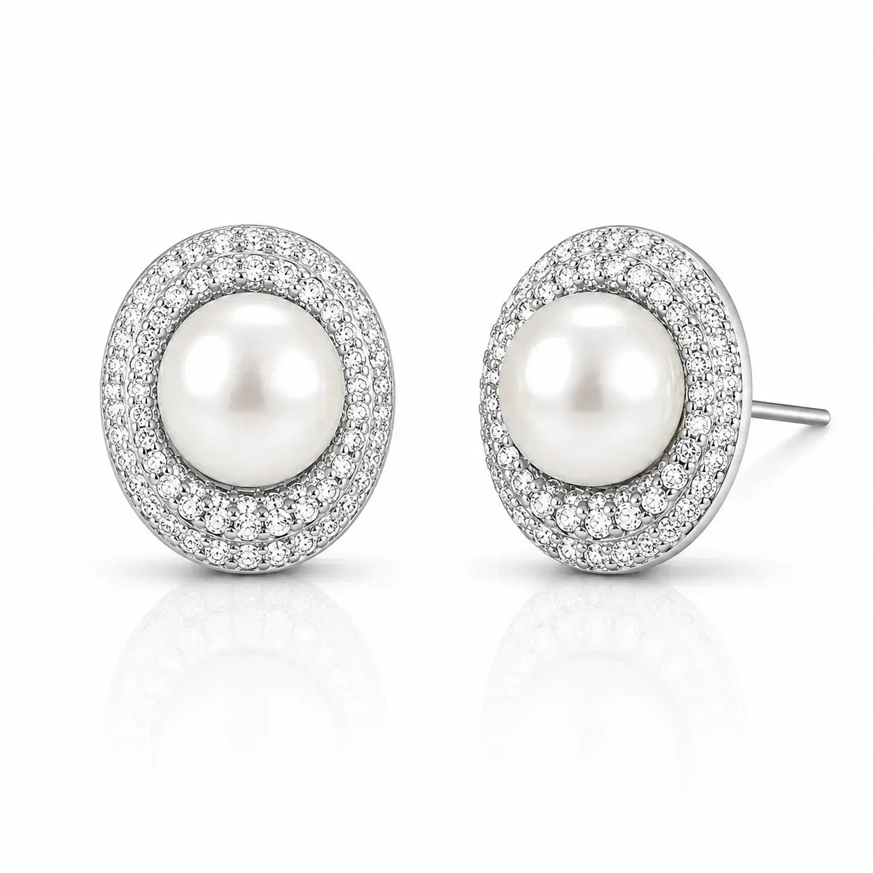 A pair of oval stud earrings featuring a central white pearl surrounded by a halo of small clear stones in a silver-toned setting, shown on a clean white background with a soft reflection below.