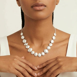Woman wearing a white pearl necklace against a neutral background