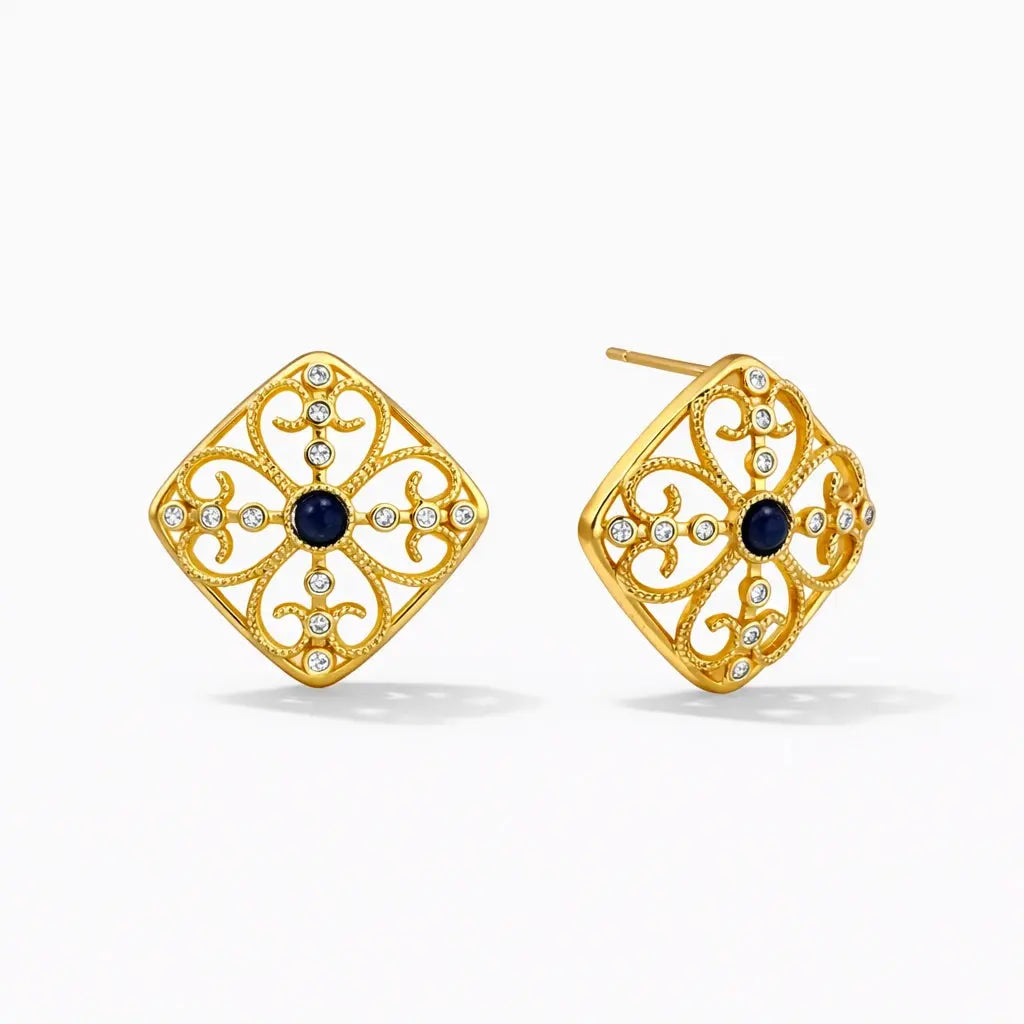 Gold stud earrings with intricate filigree, blue center stone, and clear gems on white background