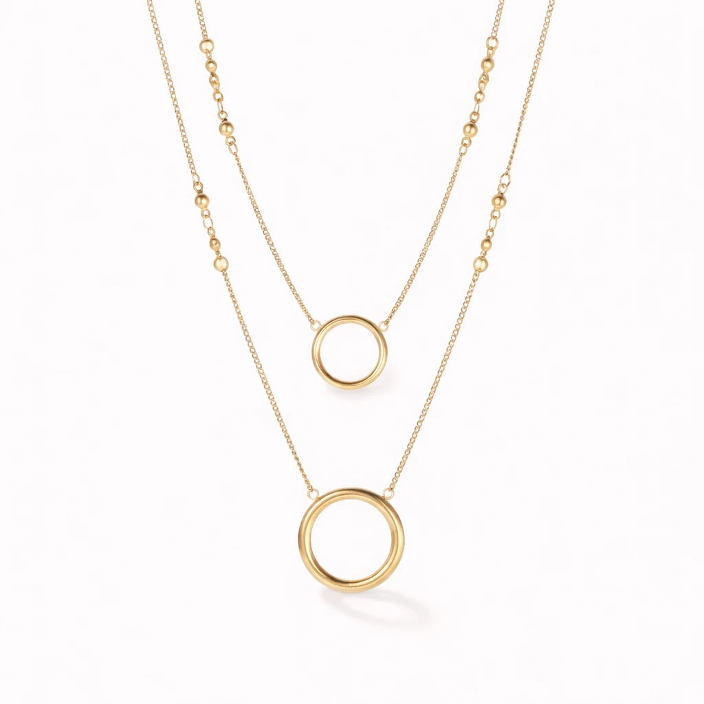 Two gold necklaces with circular pendants on a white background