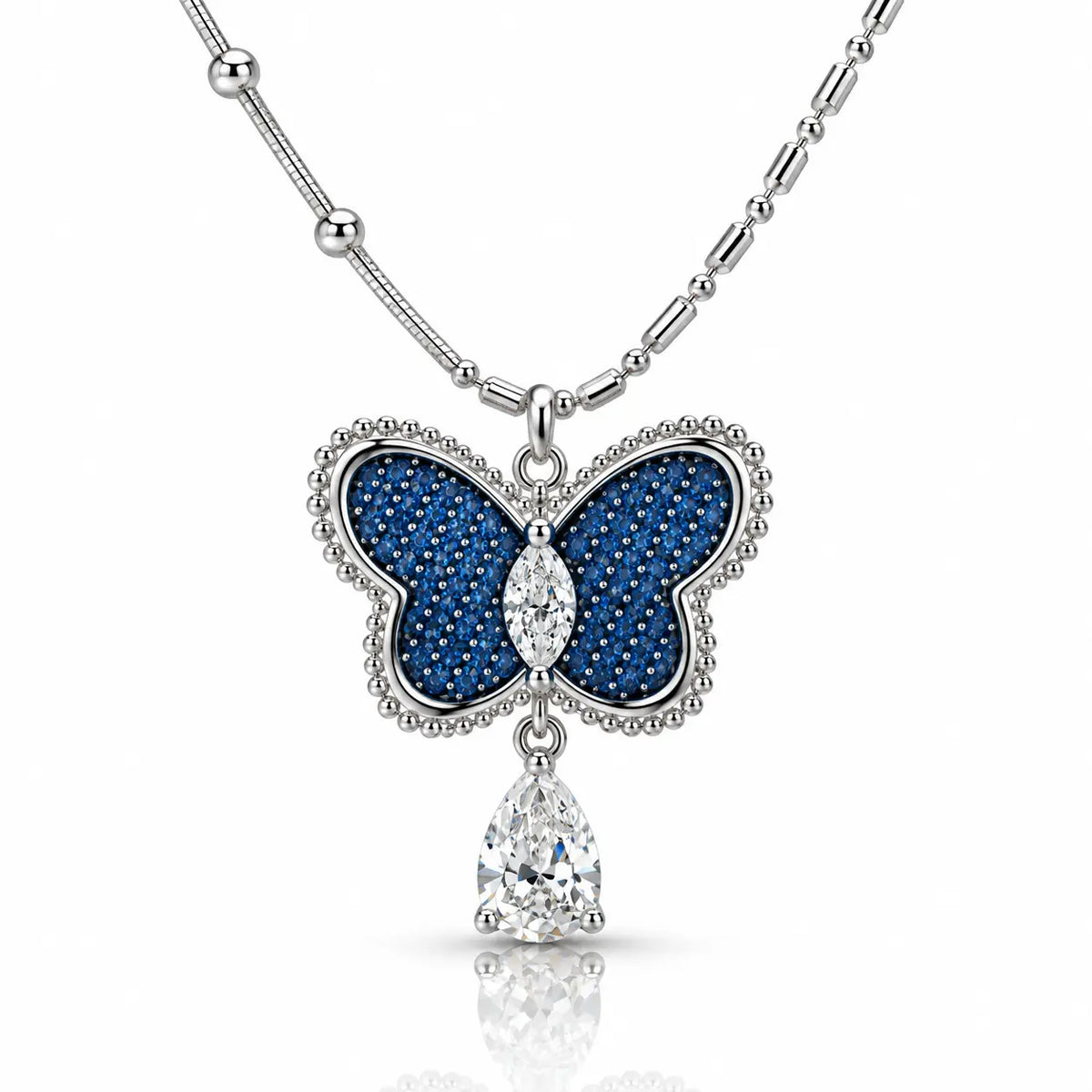 A silver butterfly pendant necklace with deep blue pavé inlay and clear teardrop gemstones, shown on a white background with a soft reflection.