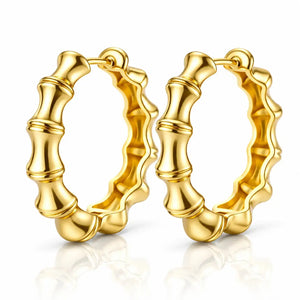 A pair of gold hoop earrings with a polished bamboo-inspired segmented design, displayed on a clean white background with a soft reflection below.