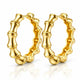 A pair of gold hoop earrings with a polished bamboo-inspired segmented design, displayed on a clean white background with a soft reflection below.