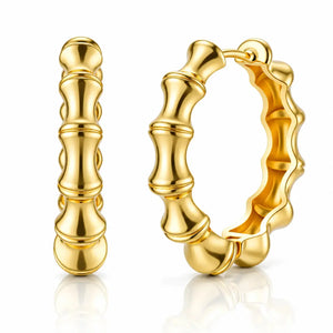 A pair of gold hoop earrings with a polished bamboo-inspired segmented design, shown on a clean white background with a soft reflection below.
