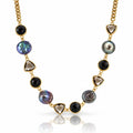 A gold chain necklace featuring alternating round black onyx beads, faceted smoky quartz triangle beads, and irregular iridescent pearl beads in gold settings, displayed on a clean white background with a soft reflection.